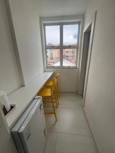une cuisine avec une fenêtre et 2 chaises jaunes dans l'établissement ECOSURF, à Cabo Frio