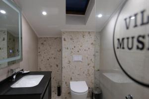 a bathroom with a sink and a toilet and a mirror at Vila Muslli in Korçë