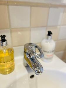 a bathroom sink with a faucet and a bottle of soap at City Mill - Next to Town Centre Shopping and Restaurants - Free Parking in Burton upon Trent