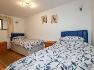 a bedroom with two beds with blue and white sheets at Duck House in Bude