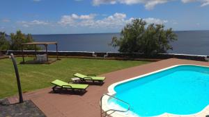 a swimming pool with two lawn chairs and a gazebo at ALLuar Lodge in Angra do Heroísmo