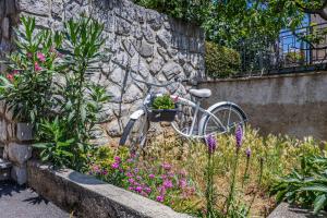 uma bicicleta estacionada ao lado de uma parede de pedra com flores em Apartments ALEXIS em Crikvenica