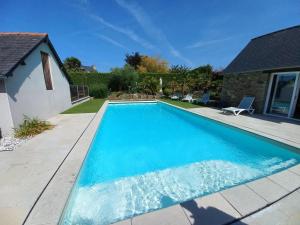 una piscina de agua azul en un patio en Kloz Ar Lore - piscine chauffée, en Plouër-sur-Rance
