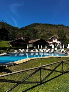a swimming pool with chairs and a fence at Fazenda Suica Le Canton in Teresópolis