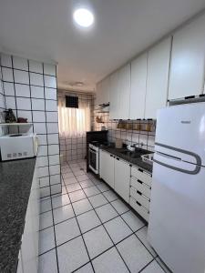 uma cozinha com armários brancos e um frigorífico branco em Apartamento próximo ao mar! em Ubatuba
