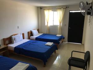 Zimmer mit 3 Betten, einem Stuhl und einem Fenster in der Unterkunft Coffee Hotel in Planadas