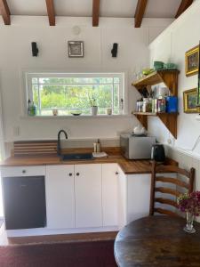 a kitchen with white cabinets and a sink and a window at Cascade Cottage in Bombay