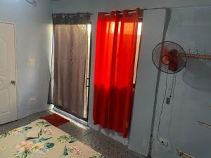 Habitación con cortinas rojas y ventilador junto a una ventana. en 1 habitation, en Boca Chica