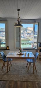 een eetkamer met een tafel en stoelen en een groot raam bij L'atelier- Duplex Vue magnifique sur le port- in Saint-Valéry-en-Caux