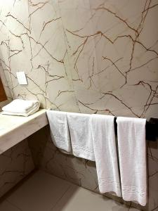 a bathroom with white towels on a marble wall at Hotel Village Porto de Galinhas - Apartamento 215 in Porto De Galinhas
