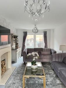 a living room with a couch and a chandelier at 5 Bedroom Luxury House with Parking for 2 Cars in Desborough