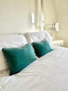 Una cama blanca con dos almohadas verdes. en 5 Bedroom Luxury House with Parking for 2 Cars, en Desborough