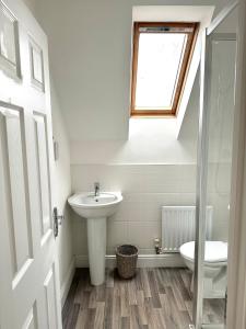 a bathroom with a sink and a toilet and a window at 5 Bedroom Luxury House with Parking for 2 Cars in Desborough
