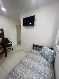 - une chambre avec un lit et une télévision murale dans l'établissement ECOSURF, à Cabo Frio