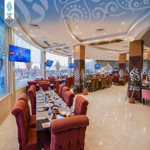 une salle à manger avec de longues tables et des chaises rouges dans l'établissement LUSINDA HOTEL MANAGEMENT BY ZAD, à Suez