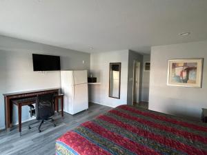 ein Hotelzimmer mit einem Bett und einem Flachbild-TV in der Unterkunft CoachLight Motel in Hemet