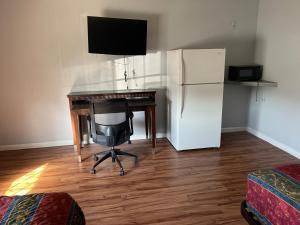 a desk with a computer and a refrigerator in a room at CoachLight Motel in Hemet +5 photos