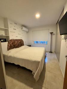 a bedroom with a white bed and a chair at Departamentos en Costanera, sobre Alem in Gualeguaychú