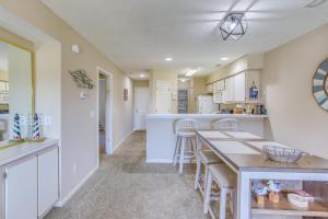 ポーリーズ・アイランドにあるPawleys Island Condo with Screened Porch and Golfing!の白いキャビネット、テーブルと椅子付きのキッチンが備わります。