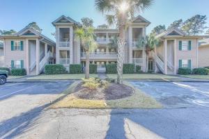 ポーリーズ・アイランドにあるPawleys Island Condo with Screened Porch and Golfing!の私道の椰子の木が茂る大家