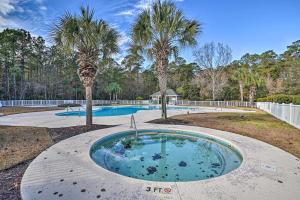 a swimming pool with two palm trees in a yard at Pawleys Island Condo with Screened Porch and Golfing! in Pawleys Island