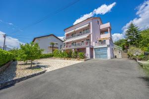 Una gran casa rosa con entrada para coches. en Apartments ALEXIS, en Crikvenica