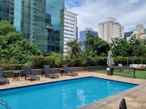 a swimming pool with chairs and tables and buildings at Max Savassi Luxury in Belo Horizonte