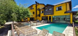 a pool in front of a yellow building with chairs at Complejo Base 41 in San Carlos de Bariloche