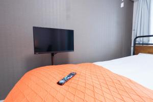 einen TV auf einem Bett mit Fernbedienung in der Unterkunft Seaside Tamachi - Vacation STAY 15580 in Tokio