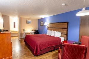 Habitación de hotel con cama roja y paredes azules en Motel Puyallup, en Puyallup