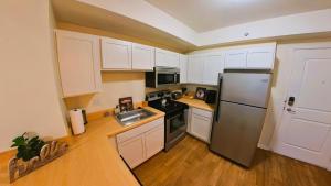a kitchen with white cabinets and a stainless steel refrigerator at Prime City Center Location! 2BR Near Everything! in Detroit