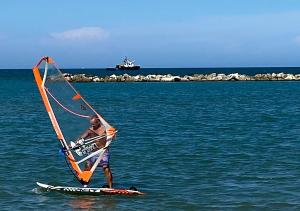 a man on a surfboard with a sail on the water at Casa Dolci Rodolfo 4km from the sea in Montemarciano