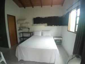 a bedroom with a white bed and a window at Chalé Nova Aurora in Alto Paraíso de Goiás