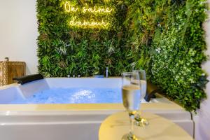 a glass of wine sitting on a table next to a bathtub at L'Eden Zen - Suite Jacuzzi, parking, clim, Netflix in Béziers