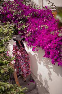a woman in a dress and hat walking down a staircase with pink flowers at Lijiang Flowers Valley Inn in Lijiang