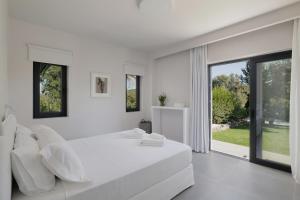 a white bedroom with a large bed and large windows at Myrtia - Luxury Hidden Gem in Corfu Town +35 photos