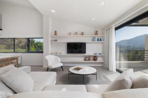 a living room with white furniture and a large window at Myrtia - Luxury Hidden Gem in Corfu Town