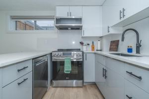 a white kitchen with a stove and a sink at Central Edmonton Family Friendly Home in Edmonton