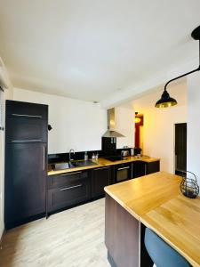 a kitchen with black cabinets and a wooden counter top at Appartement F3 - Palais de Justice in Le Havre