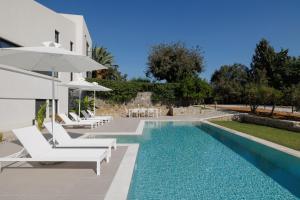 a villa with a swimming pool with chairs and an umbrella at Myrtia - Luxury Hidden Gem in Corfu Town