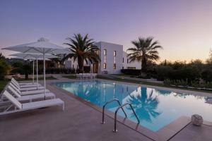 a swimming pool with two chairs and an umbrella at Gaia - A Secret Luxury Hideaway in Achílleion