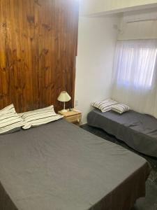 2 camas en una habitación con paredes de madera y ventana en Departamento Zuni, en San Pedro