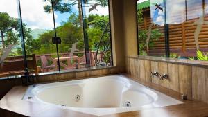 a large bath tub in a bathroom with a window at Chalés Mirante das Pedras in Monte Verde