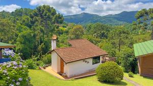 uma pequena casa num jardim com montanhas ao fundo em Chalés Mirante das Pedras em Monte Verde
