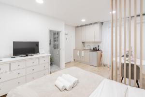 a white bedroom with a bed and a tv at Classy & Cozy apartment in Ljubljana