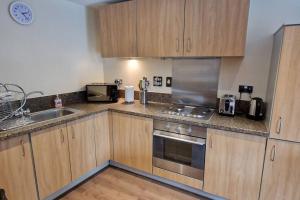 a kitchen with wooden cabinets and stainless steel appliances at 2 Bedroom Apartment Central Birmingham City Centre ( Parking ) in Birmingham