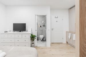 a white bedroom with a television and a bathroom at Classy & Cozy apartment in Ljubljana