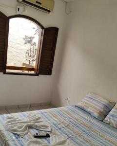 a bedroom with a bed and a window with a remote control at Pousada Encantos de Maceió in Maceió