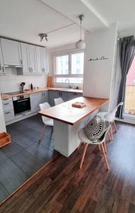 イシー・レ・ムリノーにあるCocon familial proche de Parisの白いキャビネット、木製テーブルと椅子付きのキッチンが備わります。