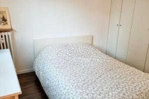 a small bedroom with a bed with a white comforter at Cocon familial proche de Paris in Issy-les-Moulineaux